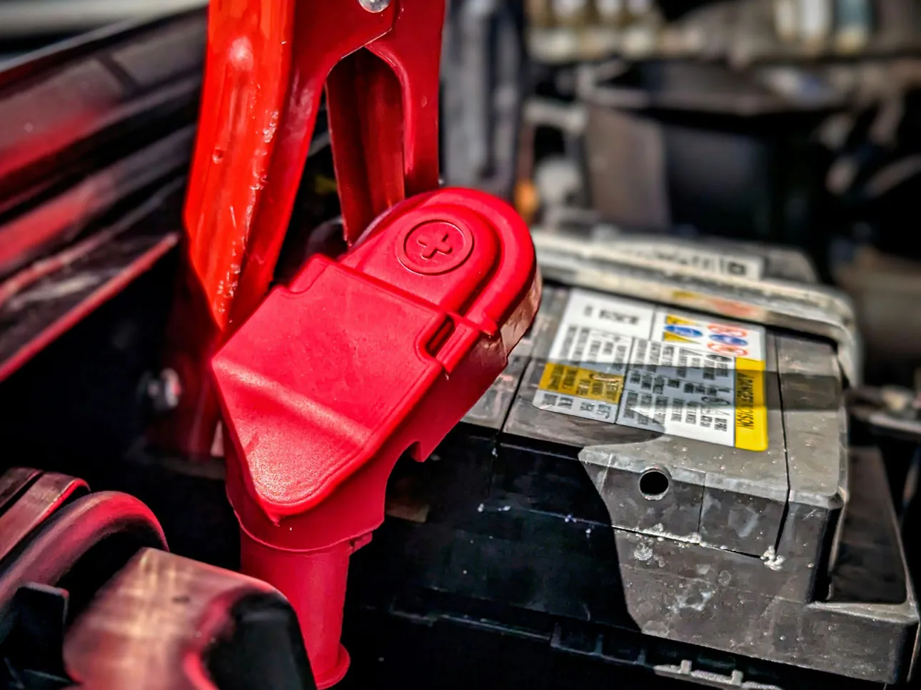 A jump lead connected securely to a car battery terminal.
