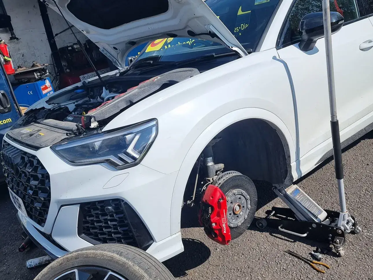 A vehicle supported safely while a mobile mechanic works on the wheel area.